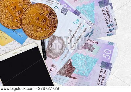 50 Ukrainian Hryvnias Bills And Golden Bitcoins With Smartphone And Credit Cards. Cryptocurrency Inv