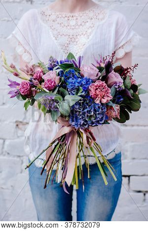 A Bouquet Of Flowers In The Hands Of A Woman On A Light Background. Bouquet Of Eucalyptus, Carnation