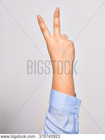 Hand of caucasian young woman doing victory symbol showing number two with streched fingers raised up over isolated white background