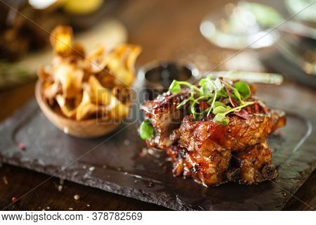 Pork ribs cooked at low temperature. Blackcurrant sauce, parsnip chips with Parmesan cheese. Delicious healthy meat food closeup served on a table for lunch in modern cuisine gourmet restaurant.