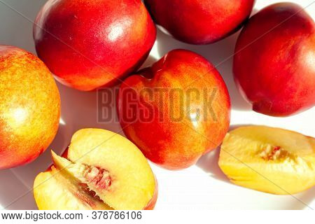 Red Ripe Organic Nectarine Fruits On The White Plate On Nature Background. Summertime Healthy Eating
