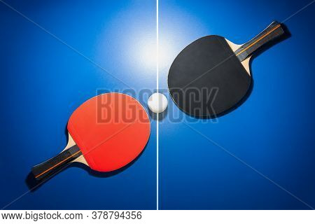 Top View Black And Red Table Tennis Racket And A White Ping Pong Ball On The Blue Ping Pong Table Wi
