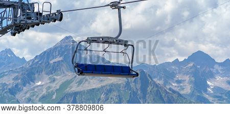 Cableway On Mountaintop In Cloudy Weather. Modern Ropeway With Benches In Amazing Mountainous Terrai