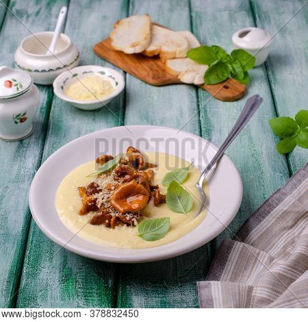 Traditional Polenta With Mushrooms And Cheese In A Dish On A Green Wooden Background. Selective Focu
