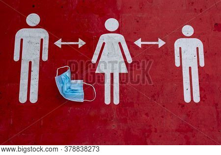 A Crumpled Protective Mask Lies On A Red Sign That Informs People To Keep A Social Distance. Sign In
