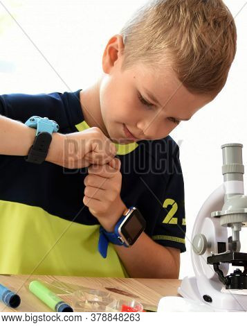 Boy Sitting And Looking Through A Microscope