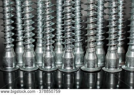 Inverted Screws Upside Down On A Dark Background With A Reflection At The Bottom