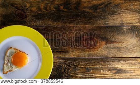 Fried Yolk On Round Ceramic Plate With Yellow Edge On Rough Wooden Background Or Table. Copy Space F