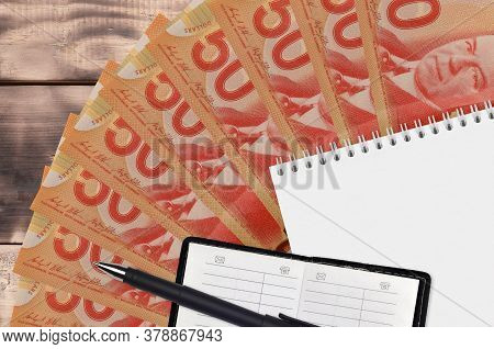 50 Canadian Dollars Bills Fan And Notepad With Contact Book And Black Pen. Concept Of Financial Plan