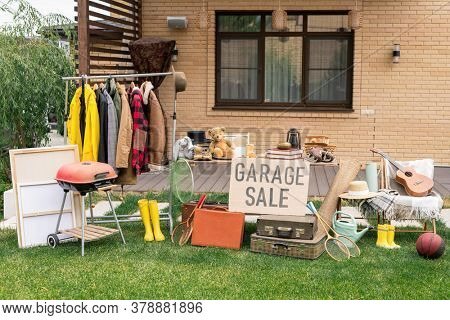 Garage sale in backyard: various toys, household stuff and clothes putting on sale