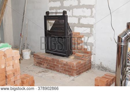Black Cast Iron Firebox With A Lift Door Stands On The Brickwork In The Living Room