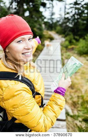 Woman Hiking And Reading Map In Forest
