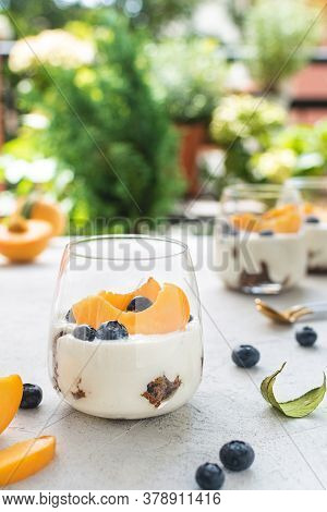 Individual Layered Desserts With Sponge Cake, Cream And Peach Fruit, Blueberry, Trifle