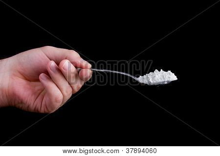 Hand Holding A Spoon Full Of A White Powder