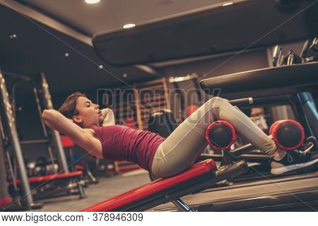 Active Young Woman Working Out In Gym, Doing Incline Bench Sit Ups, Strengthening Core And Abdominal