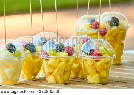 Plastic Cup With Fruits Like Pineapple And Blackberries On The Counter.