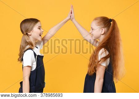 Two Young Little Girls 12-13 Years Old In White T-shirt Blue School Uniform Dresses Isolated On Yell