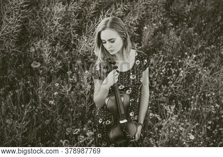 A Young Blonde European Thin Girl Stands In The Midst Of Very Tall Purple And Poppy Plant