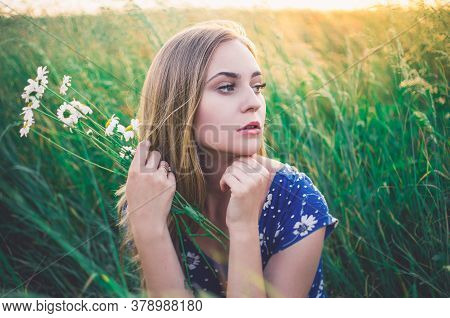 Girl Sit In Tall Grass. A Bouquet Daisies In Hand.