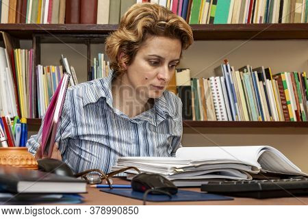 Image Of A Busy Woman Teleworking At Her Desk At The Home. Working At Home Became An Important Recom