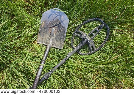 A Metal Detector And A Shovel For Searching For Coins And Precious Metal Products Lie Crossed On The