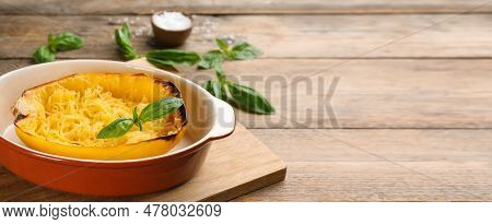 Half Of Cooked Spaghetti Squash With Basil In Baking Dish On Wooden Table. Banner Design With Space 