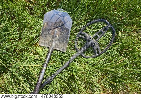 A Metal Detector And A Shovel For Searching For Coins And Precious Metal Products Lie Crossed On The