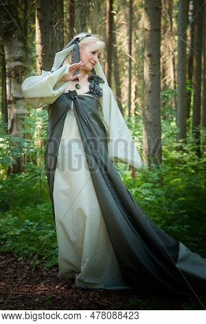 Adult Mature Woman 40-60 In A Green Long Fairy Dress In Forest. Photo Shoot In Style Of Dryad And Qu