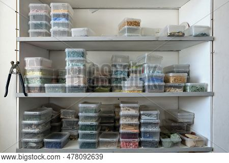 Plastic Containers With Smalt On Shelves In Closet. Regular Or Irregular Pieces Of Colored Stone Or 