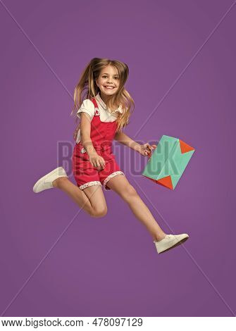 Cheerful Teen Girl Jumping After Shopping Isolated On Purple. Teen Girl Jumping After Shopping