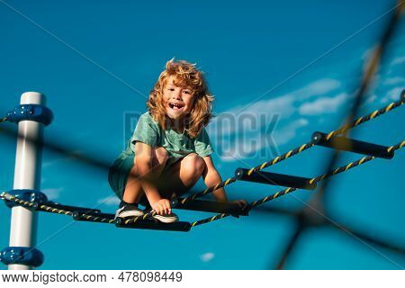 Joyful Kid Boy Having Fun On Playground Outdoors. Cute Boy Climbs Up The Ladder On The Playground. C