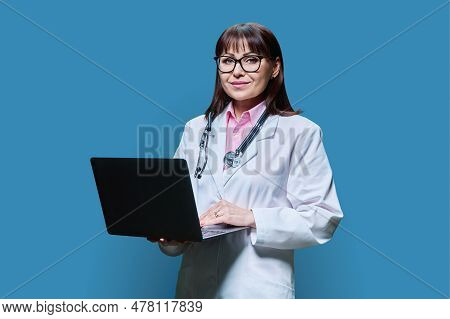 Wman Doctor Using Laptop Looking At Camera On Blue Background