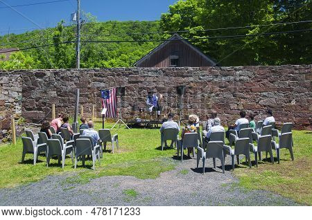 East Granby, Connecticut.  June 8, 2019. People Watching A Man Dressed Up In A Period Costume Playin