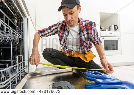 Worker Using Screwdriver To Repair Dishwasher At Home Stock Photo