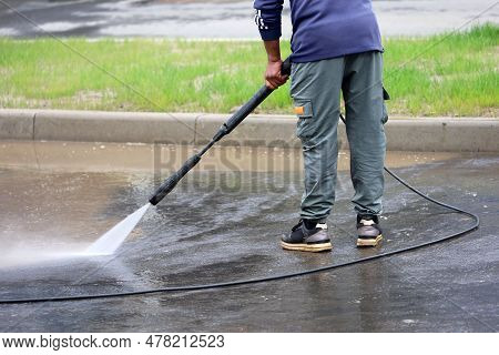 Worker Watering The Sidewalk With A Hose. Street Cleaning And Disinfection In Summer City