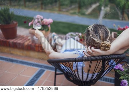 Attractive Young Woman Is Sitting On Wicker Chair In Backyard Of House. Charming Girl Is Dreaming, S
