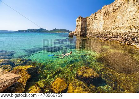 Woman Bikini Snorkeling In The Rocks Around Methoni Castle, A Medieval Fortification In Methoni Port