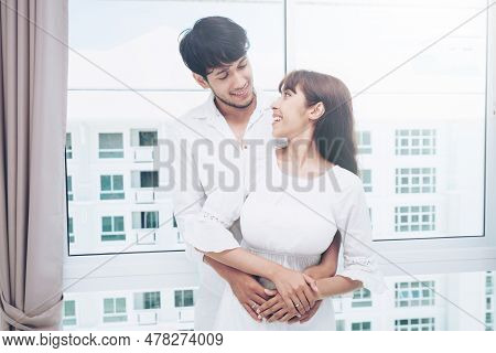 Happy Young Couple Relaxing In Home Bedroom After Waking Up In The Morning.