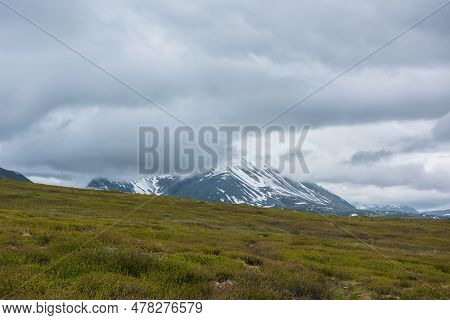 Dramatic Alpine Landscape With Snowy Mountains In Gray Low Clouds. Bleak Atmospheric Scenery Of Tund