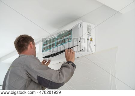 Electrician Professional Man Technician In Uniform Installing Air Conditioner In Modern Apartment. M