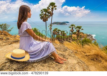 Woman Traveler Wearing Blue Dress And Straw Hat At   Phromthep Cape At Phuket In Thailand In A Summe