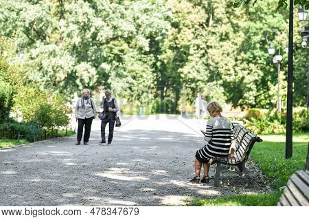 Vilnius, Lithuania - August 31, 2017: Public Park In Lithuania, Vilnius. Old Woman Sitting On The Be