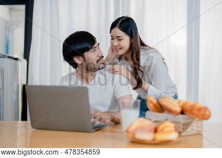 Happy Young Loving Family Couple Looking At Laptop Computer Screen, Reading Ecipes. Wife Showing Emb
