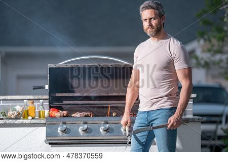 Man At A Barbecue Grill. Male Cook Preparing Barbecue Outdoors. Bbq Meat, Grill For Picnic. Roasted 