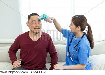 Caregiver Nurse Measuring Blood Pressure By Using Digital Sphygmomanometer Senior Patient At Home. C