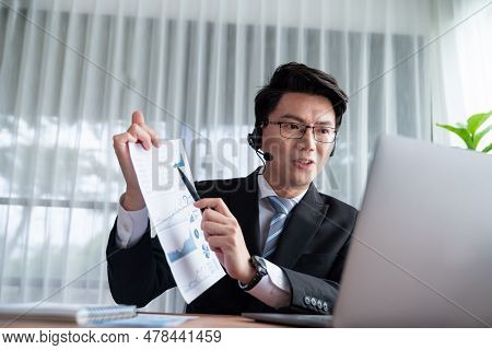 Confident Asian Telesales Businessman Work In Modern Office Wearing Headphone, Presenting Bi Dashboa