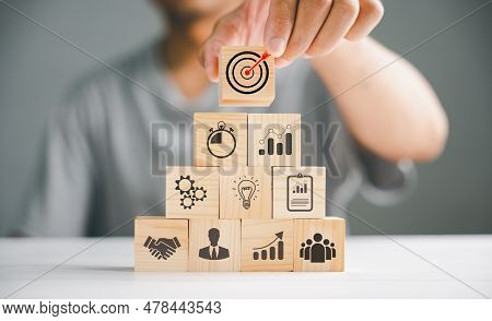 Hand Stack Of Wooden Blocks On A Table, Illustrating The Concept Of Business Strategy And Action Pla