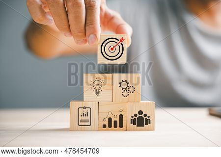 Businessmans Hand Meticulously Arranging Wood Blocks, Symbolizing A Business Strategy And Action Pla