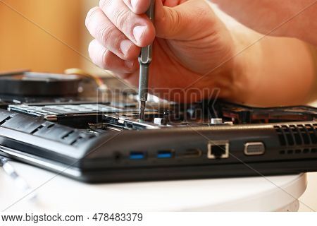 Repaiman With Screwdriver Fixing Disassembled Laptop Parts. Technical Support And Fixing Gadgets Pro