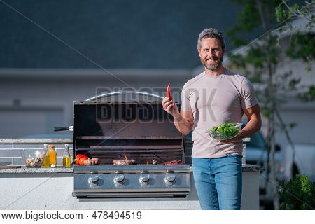 Man Cooking Meat On Barbecue In The Backyard Of The House. Handsome Man Preparing Barbecue. Barbecue